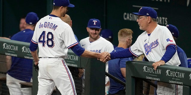El lanzador abridor de los Rangers de Texas, Jacob deGrom, le da la mano al manager Bruce Bochy, a la derecha, después de trabajar contra los Reales de Kansas City en la séptima entrada de un juego de béisbol el martes 11 de abril de 2023 en Arlington, Texas.