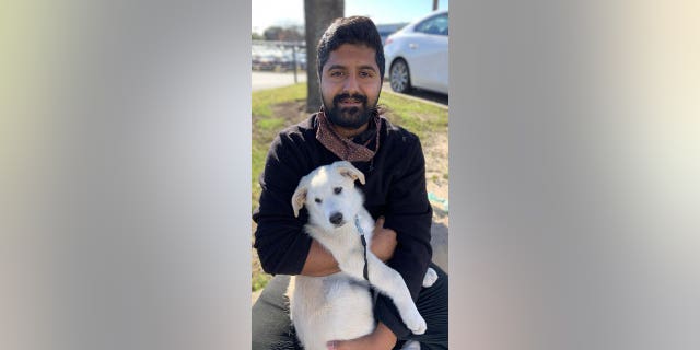 Jason John holds a white dog