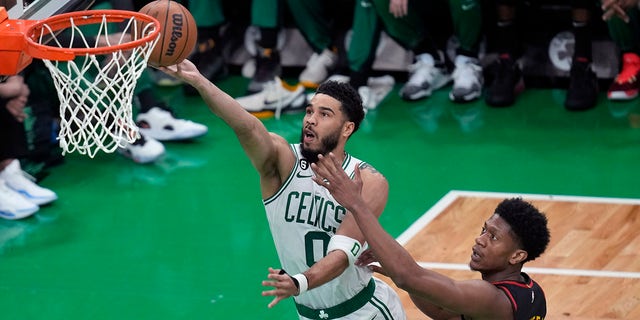 El alero de los Boston Celtics, Jayson Tatum (0), se dirige a la canasta contra el alero de los Atlanta Hawks, De'Andre Hunter (12), en el Juego 2 de la primera ronda de los playoffs de baloncesto de la NBA el martes 18 de abril de 2023, en Boston. 