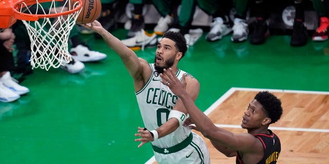 El alero de los Boston Celtics, Jayson Tatum (0), se dirige a la canasta contra el alero de los Atlanta Hawks, De'Andre Hunter (12), en el Juego 2 de la primera ronda de los playoffs de baloncesto de la NBA el martes 18 de abril de 2023, en Boston. 