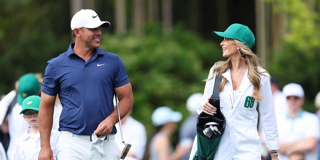 Brooks Koepka of the United States looks on with his wife, Jena Sims Koepka, during the Par 3 contest prior to the 2023 Masters Tournament at Augusta National Golf Club on April 05, 2023 in Augusta, Georgia.