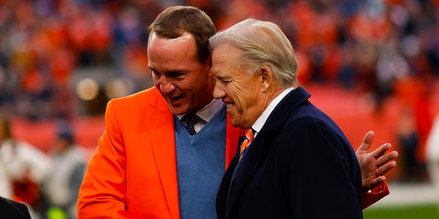 Peyton Manning, left, shakes hands with John Elway during a ceremony to enshrine Manning into the Broncos Ring of Fame during halftime of a game against the Washington Football Team at Empower Field at Mile High Oct. 31, 2021, in Denver, Colo. 