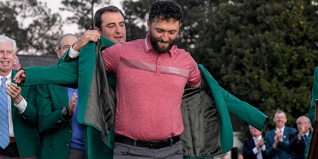 Scottie Scheffler le pone la chaqueta verde al ganador del Masters Jon Rahm en el Augusta National Golf Club el domingo 9 de abril de 2023.