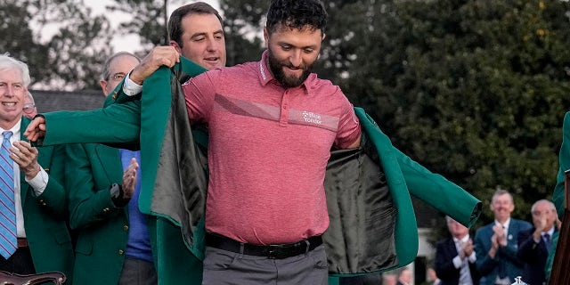 Scottie Scheffler puts the green jacket on Masters winner Jon Rahm at Augusta National Golf Club on Sunday, April 9, 2023.