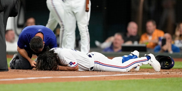 Apr 3, 2023; Arlington, Texas, USA; Texas Rangers left fielder Josh Smith (47) hits the ground after getting hit by a pitch thrown by Baltimore Orioles relief pitcher Danny Coulombe (not shown) during the third inning at Globe Life Field.