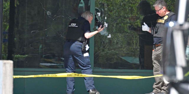 A Louisville Metro Police Department technician photographs bullet holes in the front glass of the Old National Bank building in Louisville, Kentucky, on April 10, 2023.