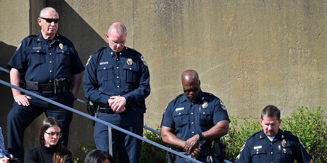 Officers with the Louisville Metro Police Department participate in a moment of silence during a vigil for the victims of Monday's shooting at the Old National Bank in Louisville, Kentucky, on April 12, 2023. 