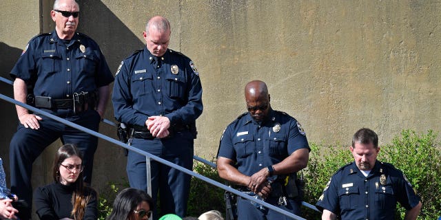Officers with the Louisville Metro Police Department participate in a moment of silence during a vigil for the victims of Monday's shooting at the Old National Bank in Louisville, Kentucky, on April 12, 2023.