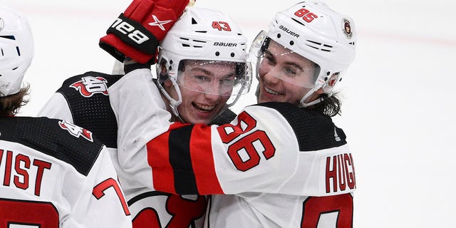 El defensa de los New Jersey Devils, Luke Hughes, y su hermano Jack Hughes celebran el jueves 13 de abril de 2023 en Washington.