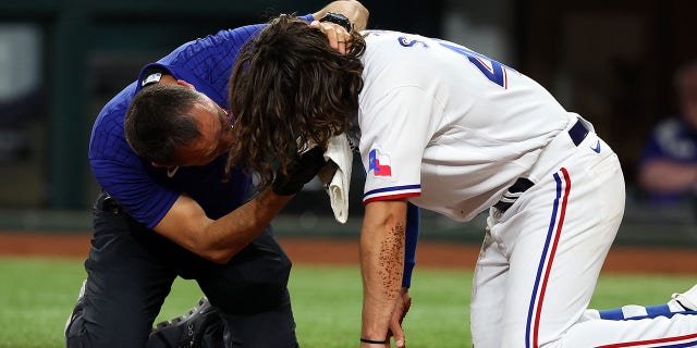 Matt Lucero, athletic trainer for the Texas Rangers, meets Josh Smith #47 after he was hit in the face by a pitch in the third inning against the Baltimore Orioles at Globe Life Field on April 03, 2023 in Arlington, Texas.