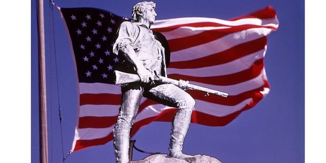 The Lexington Minuteman Statue superimposed in American flag against blue sky. Lexington Common, Massachusetts.  