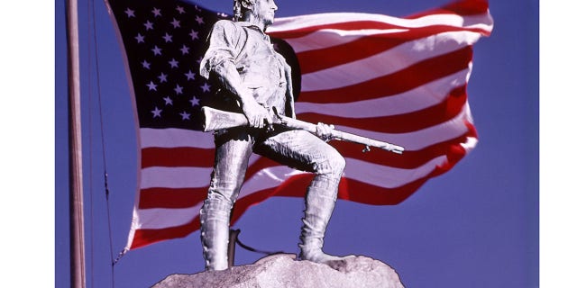 The Lexington Minuteman Statue superimposed in American flag against blue sky. Lexington Common, Massachusetts.