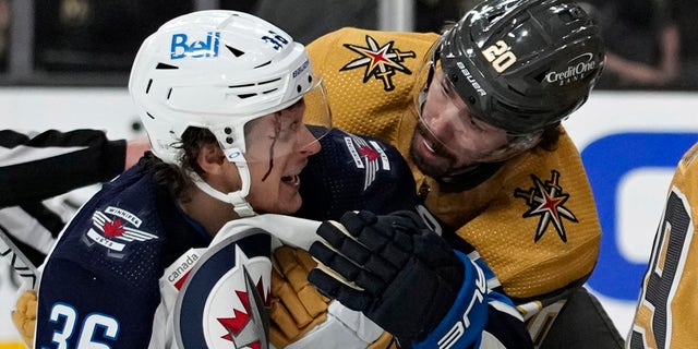 Vegas Golden Knights center Chandler Stephenson, #20, helps Winnipeg Jets center Morgan Barron, #36, after Barron cut his face on a skate during the first period of Game 1 of an NHL hockey Stanley Cup first-round playoff series Tuesday, April 18, 2023, in Las Vegas.