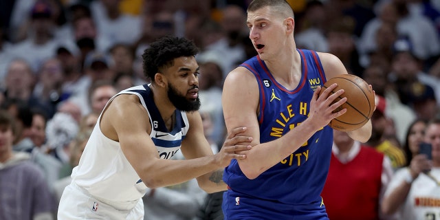 Denver Nuggets'ın 15 numaralı Nikola Jokic, 16 Nisan 2023'te Denver, Colorado'da düzenlenen NBA Playoffları 1. Tur 1. Maçının ilk çeyreğinde Minnesota Timberwolves'tan 32 numaralı Karl-Anthony Towns tarafından korunuyor.