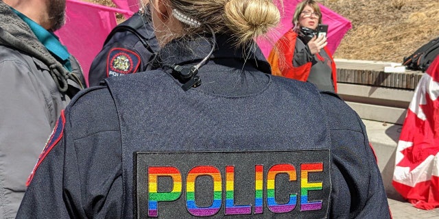 An officer at the Calgary event wears a vest decorated with "Police" in rainbow letters.