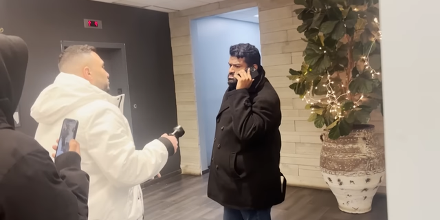 Anand Singh talking into cellphone while approached by reporter