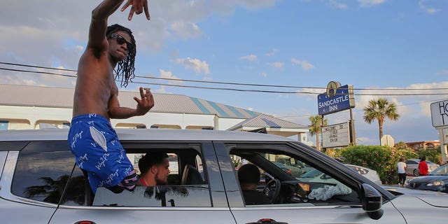A partygoer leans out of his car window during stopped traffic at Orange Crush