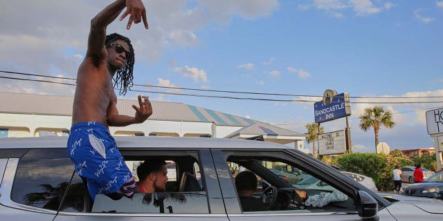 A partygoer leans out of his car window during stopped traffic at Orange Crush