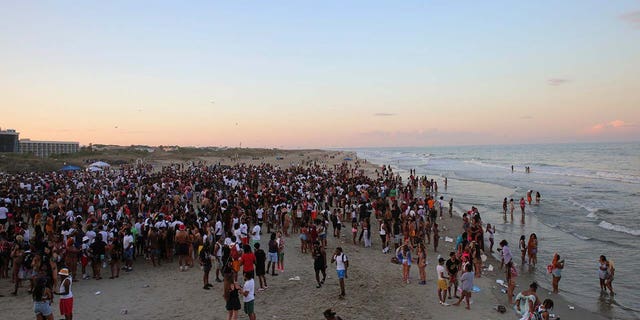 A large crowd of people enjoy Tybee Beach at sunset
