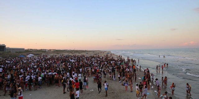 A large crowd of people enjoy Tybee Beach at sunset