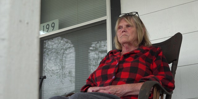 Woman sits in chair on porch