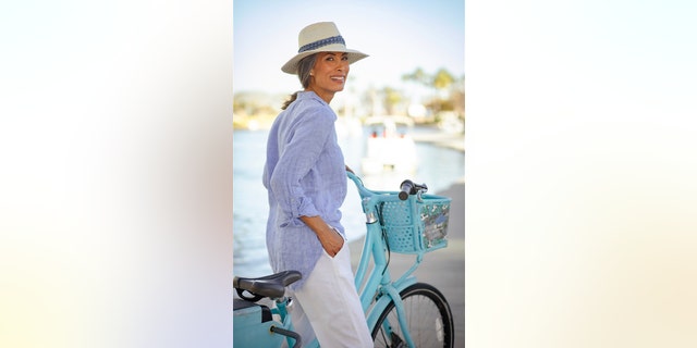 Nina Cash wearing a light blue and white pants with a matching hat on a light blue bike