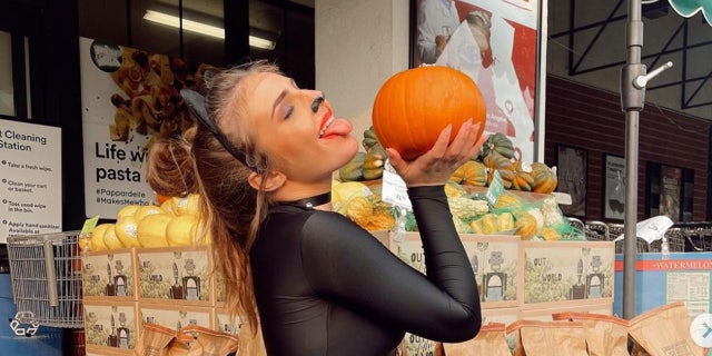 Piper Rockelle kisses a pumpkin wearing a catsuit and ears.