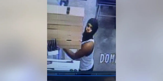 Police say this male wearing a white tank top and a black mask covering his head and face was observed with a rifle-style BB gun from the sporting goods section of the store and was possibly loading the BB gun with BB pellets.