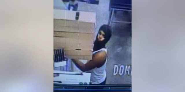 Police say this male wearing a white tank top and a black mask covering his head and face was observed with a rifle-style BB gun from the sporting goods section of the store and was possibly loading the BB gun with BB pellets.