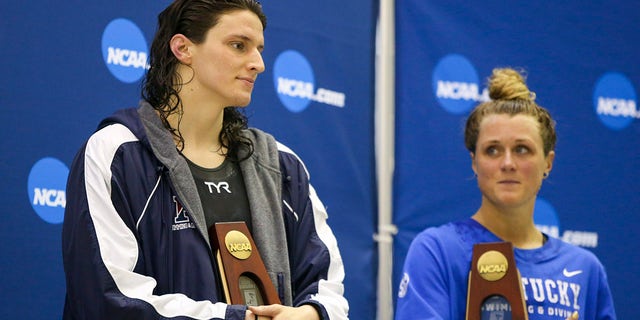 Penn Quakers swimmer Lia Thomas holds a trophy after finishing fifth in the 200 free at the NCAA Swimming &amp; Diving Championships as Kentucky Wildcats swimmer Riley Gaines looks on at Georgia Tech.