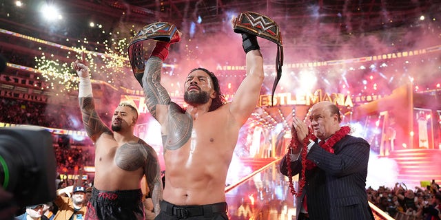 Roman Reigns, center, holds up his WWE Heavyweight and Universal Championship belts after defeating Cody Rhodes in the main event of WrestleMania 39 on Sunday, April 2, 2023 at SoFi Stadium in Inglewood, California.