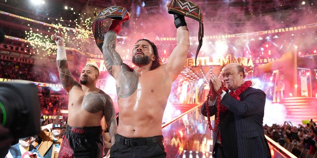 Roman Reigns, center, holds up his WWE Heavyweight and Universal Championship belts after defeating Cody Rhodes in the main event of WrestleMania 39 on Sunday, April 2, 2023 at SoFi Stadium in Inglewood, California.