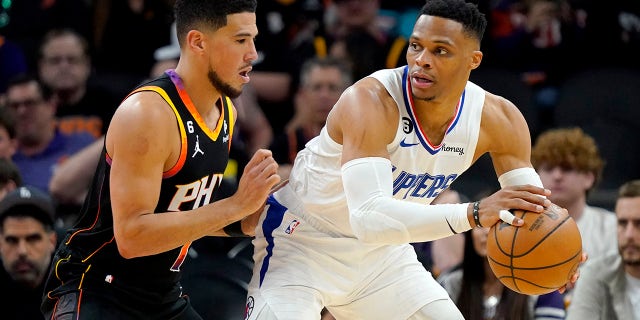 El escolta de Los Angeles Clippers, Russell Westbrook, retira al escolta de los Phoenix Suns, Devin Booker, a la izquierda, durante la segunda mitad del Juego 1 de una serie de playoffs de baloncesto de la NBA en la primera ronda, el domingo 16 de abril de 2023, en Phoenix.