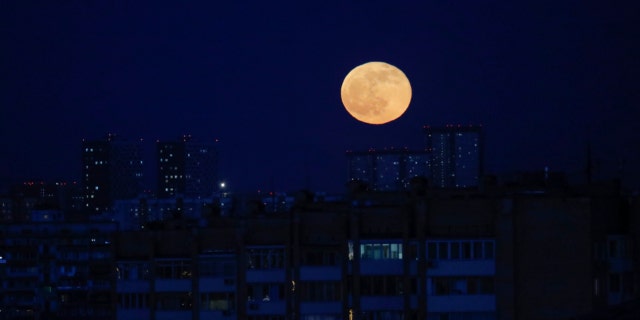 The moon rises over Moscow, Russia