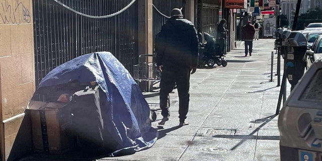 A man walks barefoot near San Francisco's City Hall in November. The city has struggled with homelessness and other public safety issues.