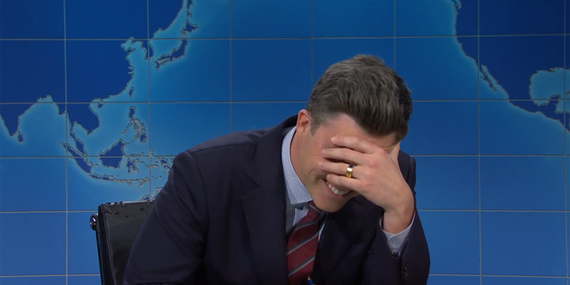 Colin Jost put his hand to his face, realizing Michael Che had pulled a prank on him.