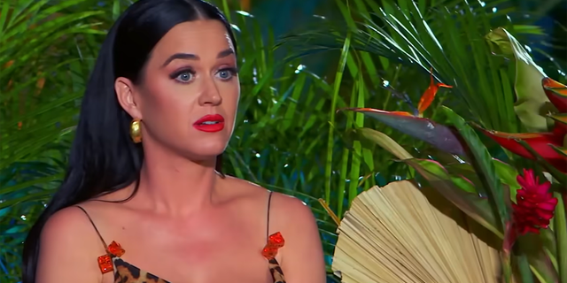 Katy Perry in a cheetah print tank top with red bows looks perplexed while watching a performance during "American Idol"