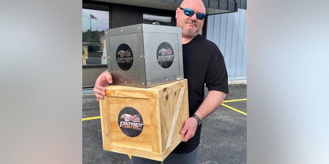 Metal Art of Wisconsin founder and Patriot Crates president Shane Henderson holding samples of his wood and steel crates.