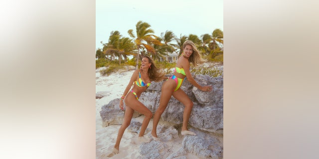 Jena Sims in a neon bikini posing next to a friend at the beach