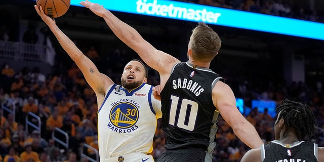 Stephen Curry shoots over Domantas Sabonis