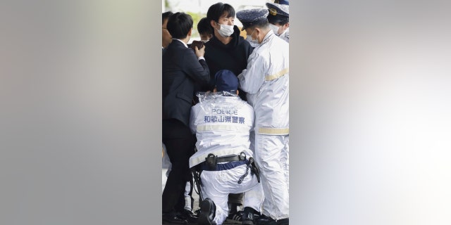 Muškarac, u sredini, uhvaćen je nakon što je nešto što je izgledalo kao dimna bomba bačeno u luku u Wakayami, zapadni Japan, u subotu, 15. travnja 2023. 