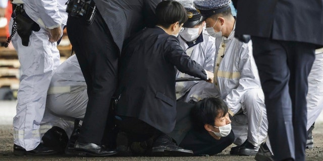 Čovjeka za kojeg se vjeruje da je osumnjičen, u sredini na zemlji, policija je uhvatila nakon što je navodno bacio "sumnjiv predmet," dok je japanski premijer Fumio Kishida posjetio luku Saikazaki za događaj izborne kampanje u Wakayami, zapadni Japan u subotu, 15. travnja 2023. 