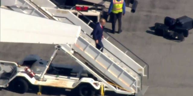 Trump exits his plane in New York to surrender in hush money payment case.