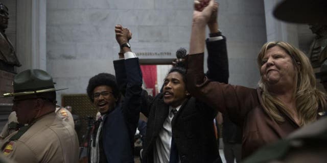 Reps. Justin Pearson, Justin Jones and Gloria Johnson hold their hands up as they exit the House Chamber doors at the state Capitol in Nashville, Tennessee on April 3, 2023.