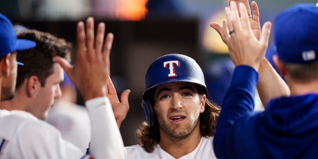 Josh Smith #47 of the Texas Rangers celebrates with teammates in the dugout during the game against the Philadelphia Phillies on Opening Day at Globe Life Field on March 30, 2023 in Arlington, Texas.