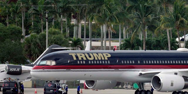 People work around the private plane of former president Donald Trump as it sits parked on the tarmac at Palm Beach International Airport, Monday, April 3, 2023, in West Palm Beach, Fla. Trump was expected to travel later in the day to New York City for his arraignment after being indicted by a Manhattan grand jury.