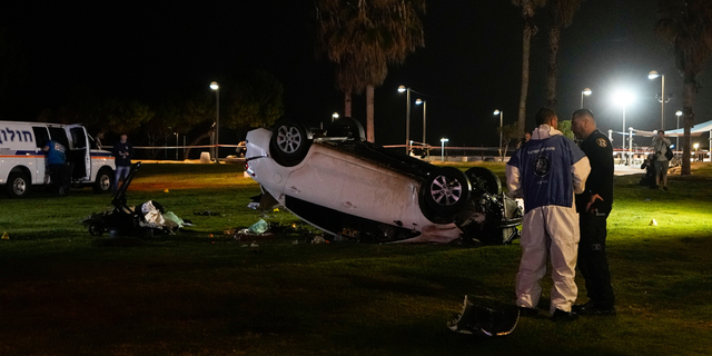 Israeli police stand at the scene of an attack in Tel Aviv, Israel, Friday, April 7, 2023. Israeli police said a car rammed into a group of people near a popular seaside park before flipping over. Police said they shot the driver of the car. Israel's rescue service described the incident as a shooting attack.