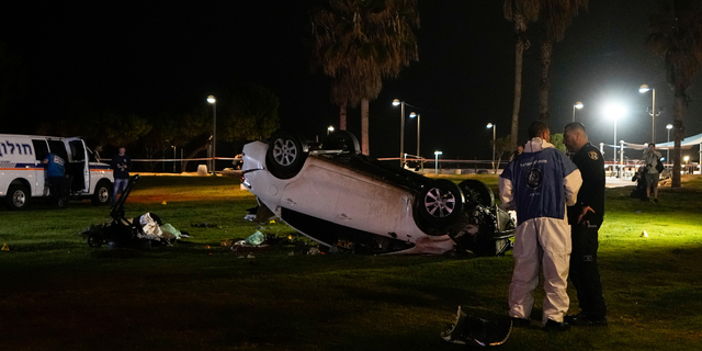 Israeli police stand at the scene of an attack in Tel Aviv, Israel, Friday, April 7, 2023. Israeli police said a car rammed into a group of people near a popular seaside park before flipping over. Police said they shot the driver of the car. Israel's rescue service described the incident as a shooting attack.