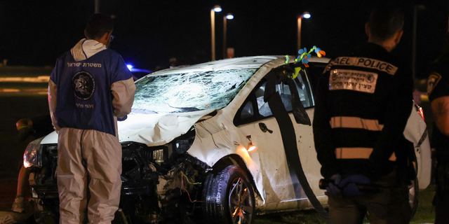 Israeli police gather next to a car used in a ramming attack in Tel Aviv on April 7, 2023. - One man was killed and four people were wounded in an attack in central Tel Aviv, Israeli rescue services said, updating a previous casualty toll of two injured. 