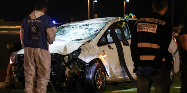 Israeli police gather next to a car used in a ramming attack in Tel Aviv on April 7, 2023. - One man was killed and four people were wounded in an attack in central Tel Aviv, Israeli rescue services said, updating a previous casualty toll of two injured.Â